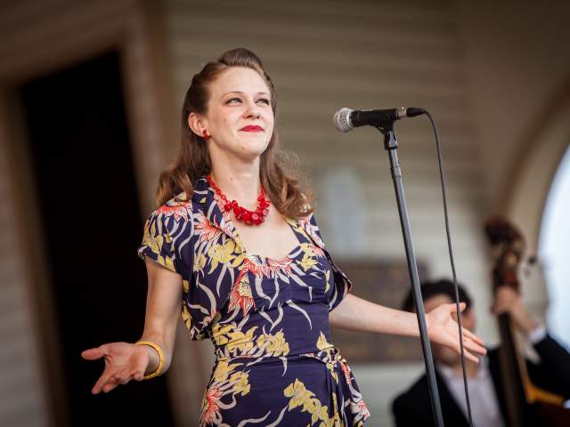 A woman stands at a microphone while performing in the New Town Concert Series in St. Charles, MO