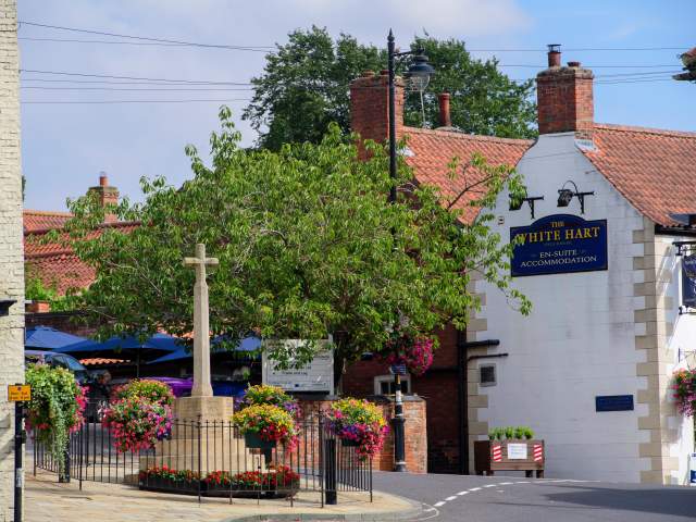 war memorial and country pub in street with flowers around it