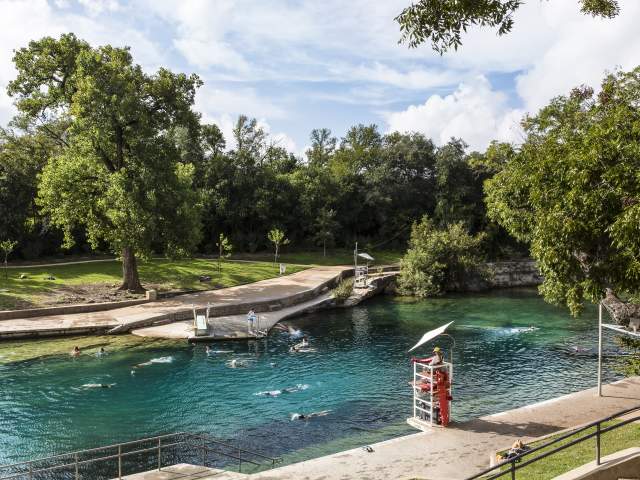 People swimming in Barton Springs Pool with lifeguard in stand