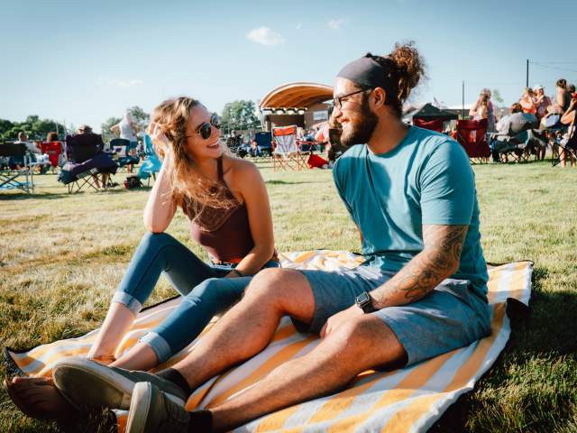 Couple sitting on a blanket at a concert in Festival Country