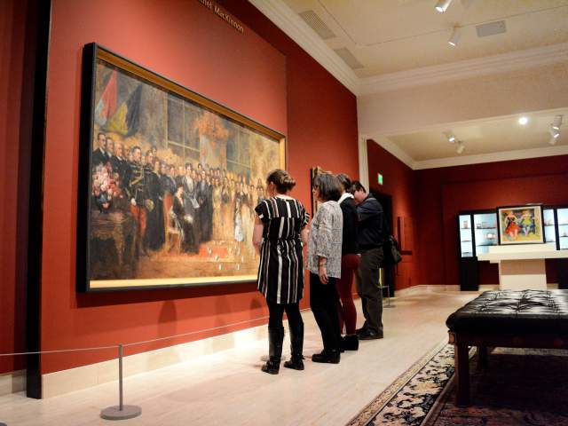 Four people stand in front of a large painting