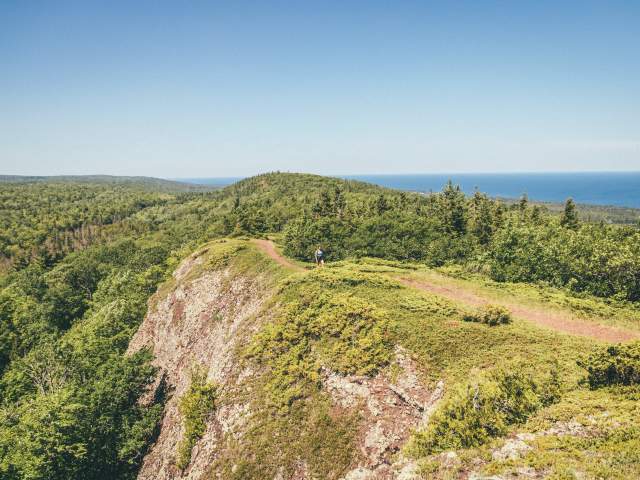 Woman hikes across a ridgeline in the Keweenaw