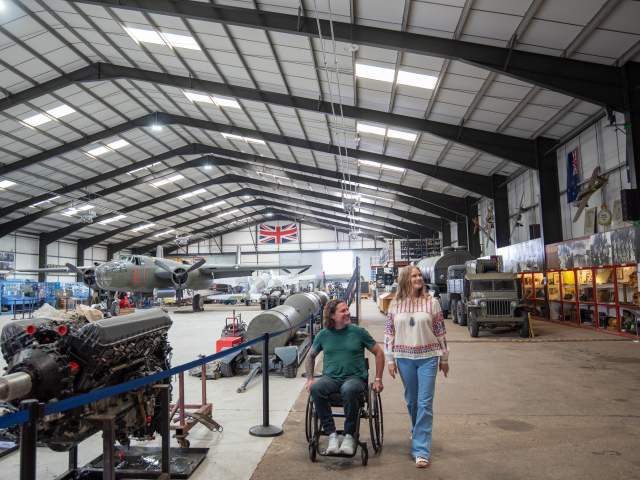 two people in a hanger with aviation props and planes in background