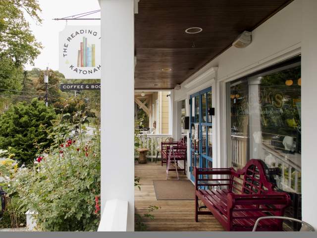 The porch of the Katonah reading room surrounded by rose bushes and with red bench seating.