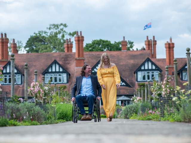 A man in a wheelchair and a woman laughing together on a path outside of Petwood Hotel