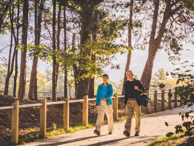 A couple walks through a sunlit path in McLain State Park.
