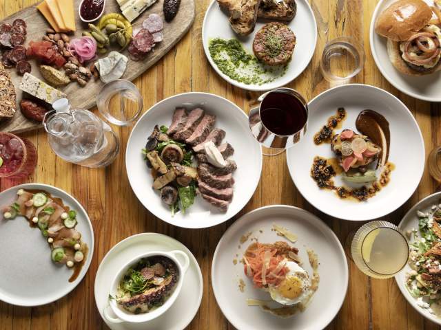 a wide array of food laid out artfully on a wooden table and shot from a birds eye view