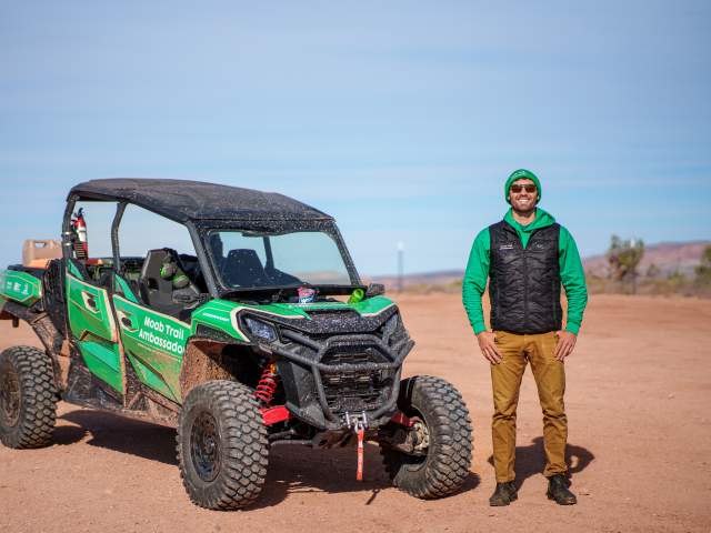 A Moab Trail Ambassador stands next to an OHV