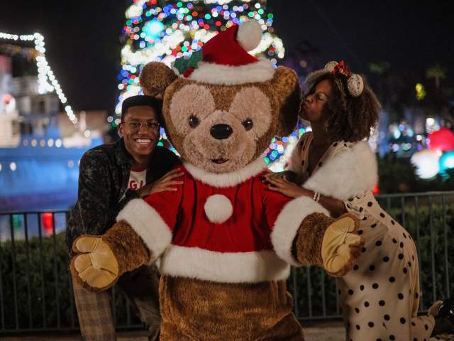 Two adults smile and pose with Santa Duffy at Disney Jollywood Nights in Orlando