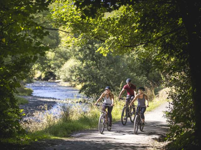 Friends biking alongside the Arrow River, Arrowtown