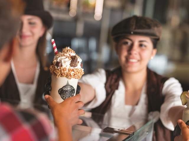 Serving a customer a milkshake at Toothsome Chocolate Emporium at Universal CityWalk
