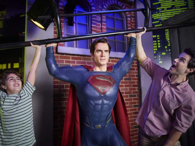 A father and son posing with Superman at Madame Tussauds in ICON Park.
