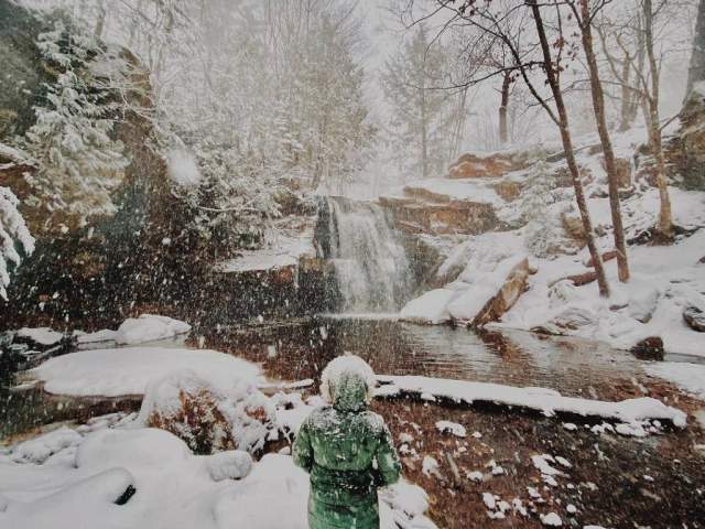 Woman standing in front of frozen waterfall.