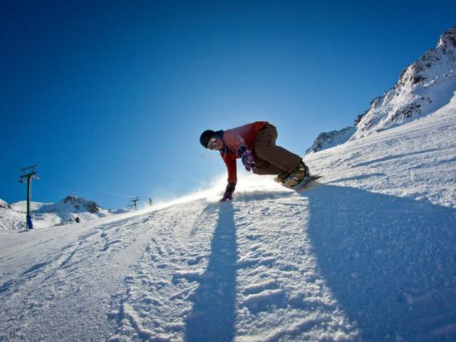 Snowboarder riding down a slope at Rainbow Ski Area