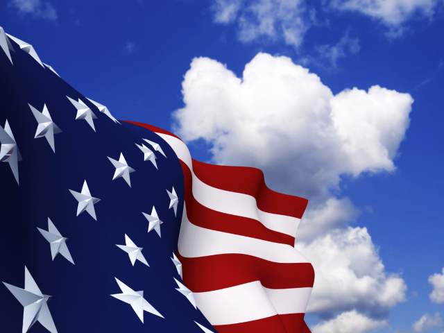 Closeup of an American flag with a blue sky background