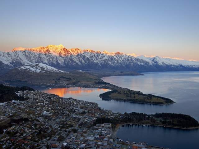 Aerial shot of Queenstown with snow capped mountains, lake and town