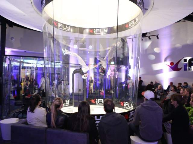 A group of people watching people indoor skydiving
