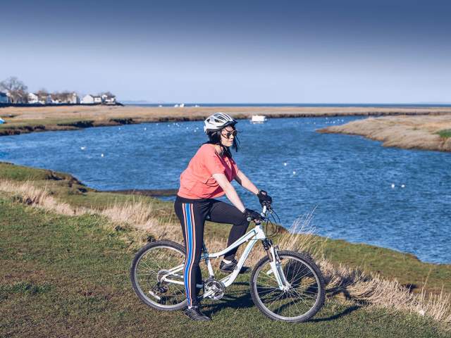 Female on a bike next to Penclawdd estuary.