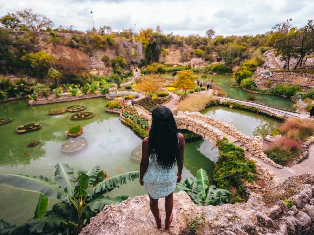 Woman overlooking lush garden and standing water