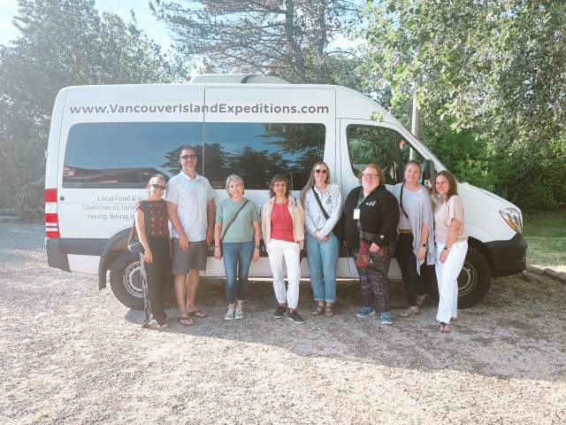 A group of people standing in front of the side of a bus.