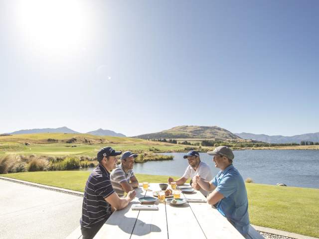 Ground of friends eating outdoors next to lake and mountains
