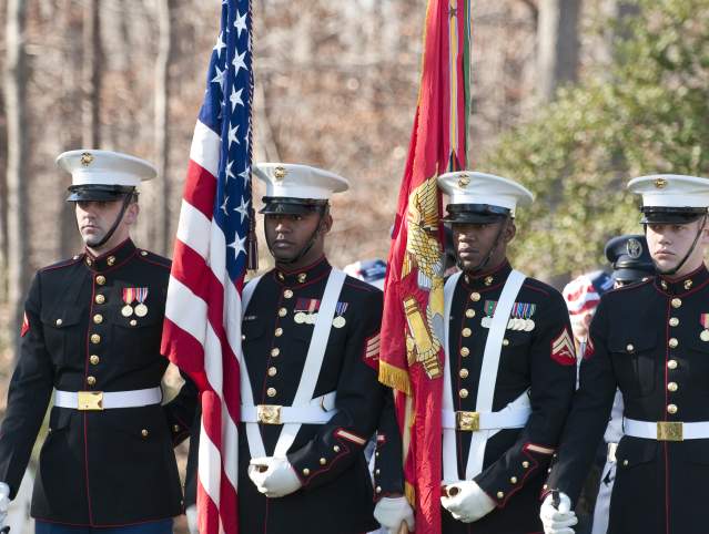 Marines in uniform holding flags for a ceremony