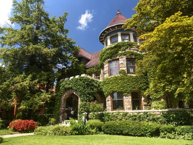 exterior of a cobblestone house covered in ivy with a yard with grass in front