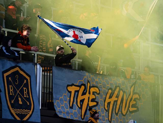Fan waving a flag after a goal at a Fort Wayne Football Club match