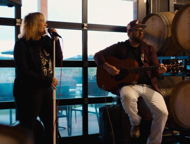 Small band playing in front of a window and wine barrels
