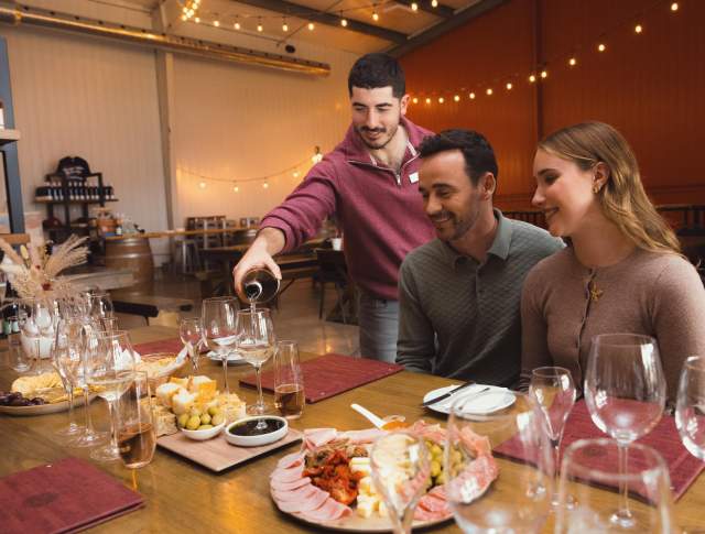 Server pouring wine for couple at a table