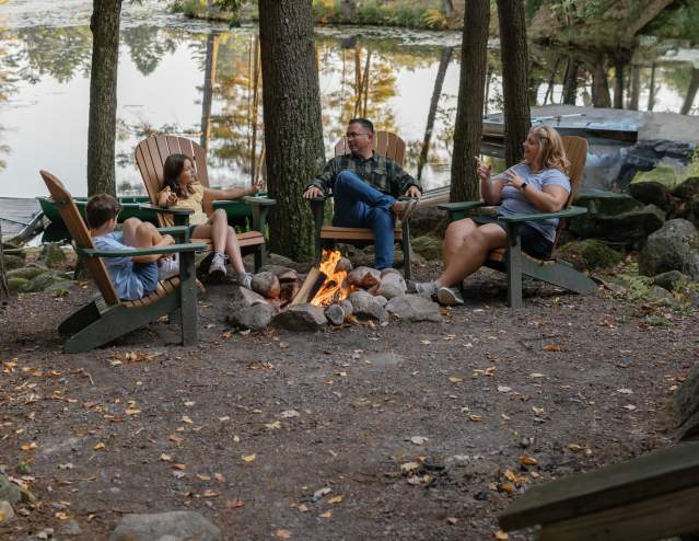 Family sitting around a campfire at Hide-A-Way Waterfront Cottages