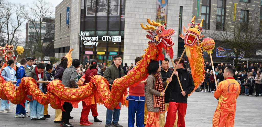 Group of people holding up paper dragon to perform lunar new year dragon dance