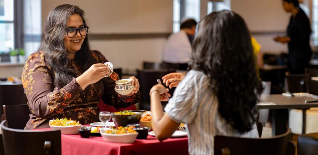 Two people sat opposite each other eating at Mint Dosa