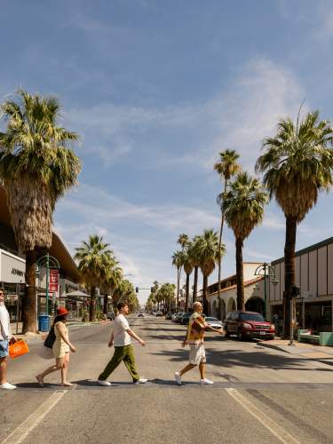 Four people crossing Palm Canyon Drive with shopping bags