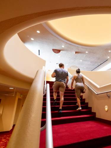 A man and a woman climb the steps inside Monona Terrace. The ceiling above them is ovular and opens up into a warm glow of light