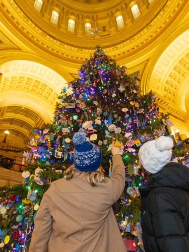 Two women look up at the large holiday tree in the Wisconsin State Capitol routunda