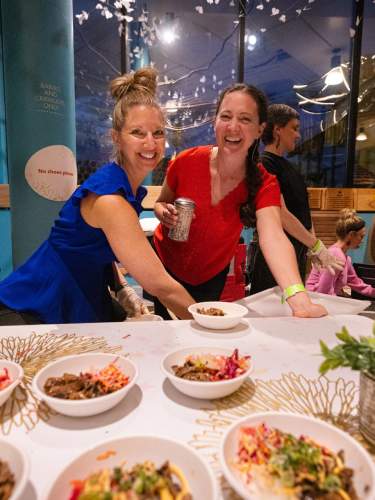 Two meeting attendees in front of catering table laughing