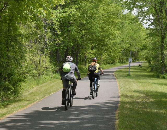 two people riding bikes on a path