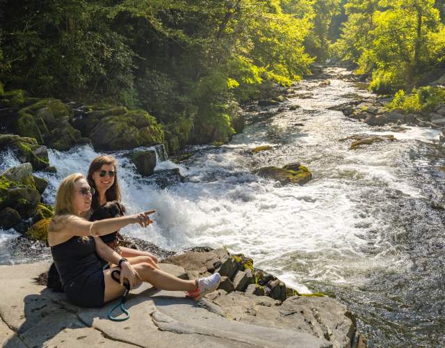 Two people sitting by rushing river