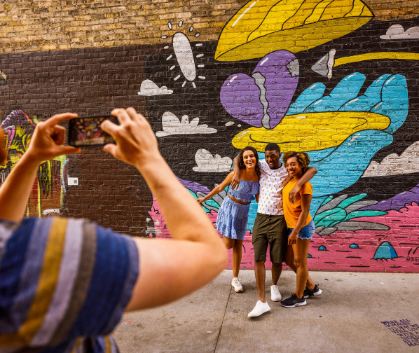 friends taking a picture in front of a colorful mural