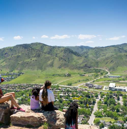 Family on a hike sitting down and looking off North Table Mountain over Golden in the Spring