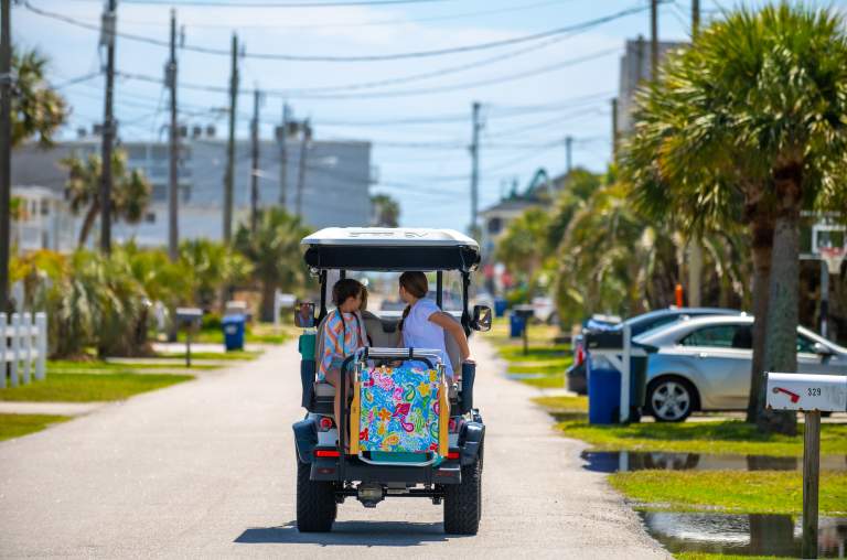 A golf cart cruises down the street in Cherry Grove