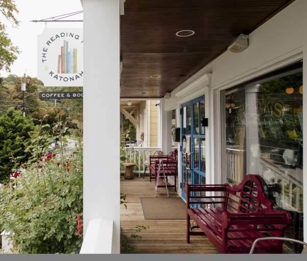 The porch of the Katonah reading room surrounded by rose bushes and with red bench seating.