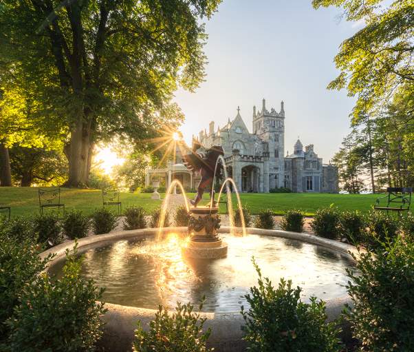 The sun sets over the Hudson River behind Lyndhurst Mansion.