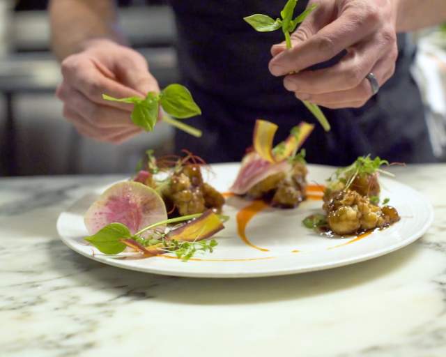 close up of hands plating a dish