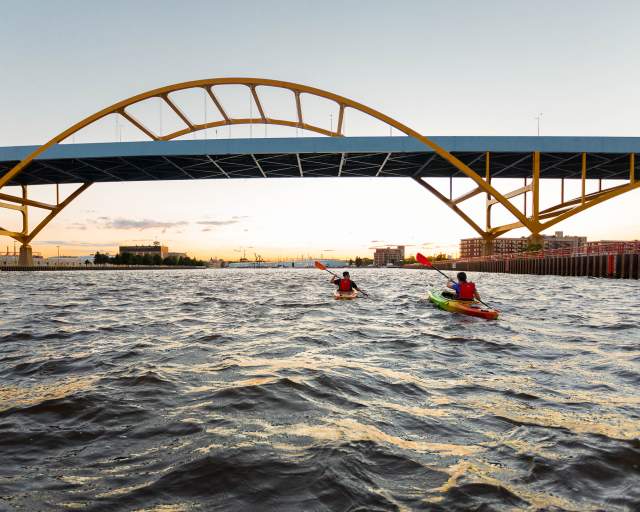 two kayakers kayaking under the Hoan Bridge