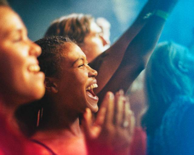 A woman in a crowd cheers with fellow fans.