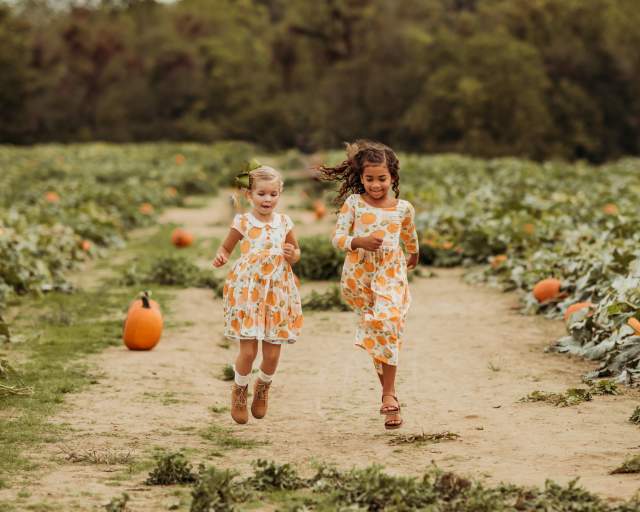 Two girls skipping through a pumpkin patch