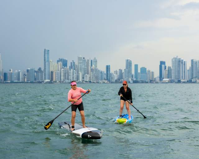 Two woman doing paddle near Taboga Island with Panama City skyline as background