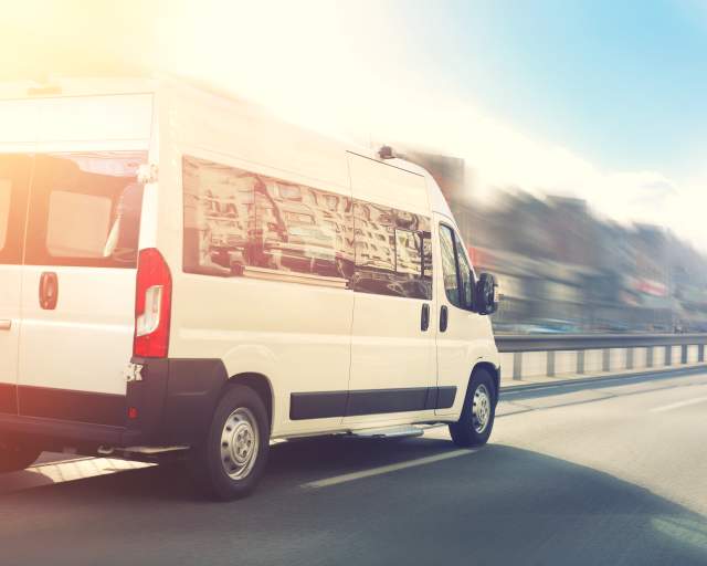 White passenger van on road with blurred background